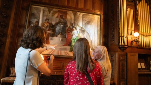 Three women in front of a Renaissance masterpiece depicting the judgement of Solomon